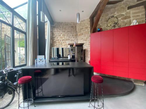 une cuisine avec des placards rouges et des tabourets rouges dans l'établissement Villa Raspail, à Ivry-sur-Seine