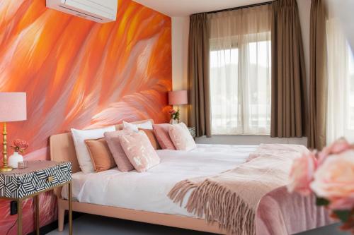 a bedroom with a large bed with a colorful wall at Dormio Wijnhotel Valkenburg in Valkenburg