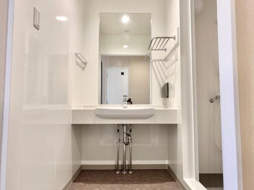 W białej łazience znajduje się umywalka i lustro. w obiekcie 阪南国际HOTEL w mieście Hannan