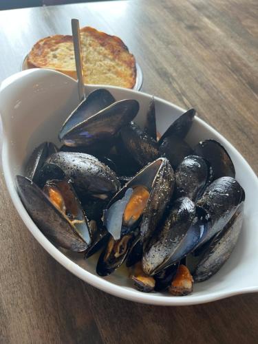 a bowl of mussels on a table with a pizza at Acadian Hotel in Stephenville