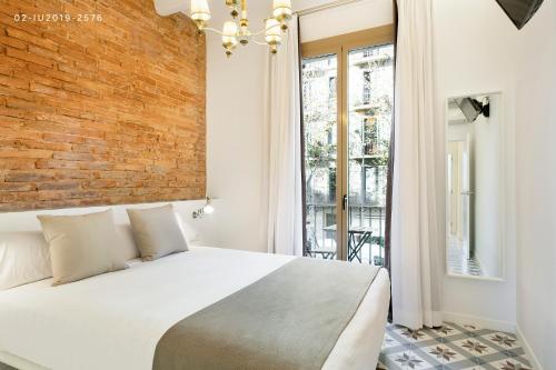 een slaapkamer met een wit bed en een bakstenen muur bij Uma Suites Sagrada Familia in Barcelona