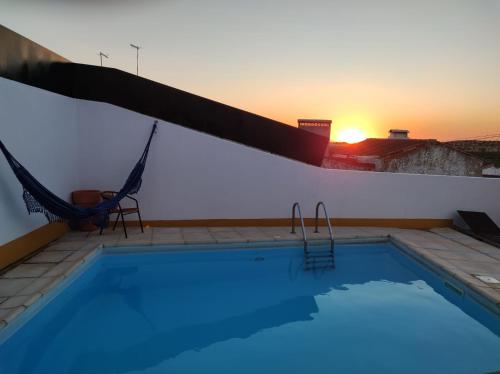 uma piscina com rede e o pôr do sol em Casa da Avó Mirinha em Figueira e Barros