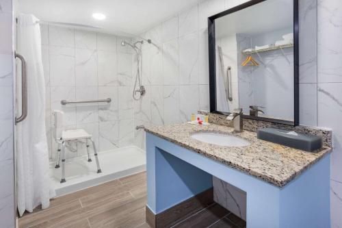 W łazience znajduje się umywalka i prysznic. w obiekcie Days Inn by Wyndham Livonia Canton Detroit w mieście Livonia