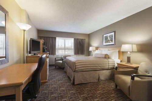 a hotel room with a bed and a desk at Travelodge by Wyndham Prince George in Prince George