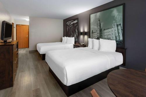a hotel room with two beds and a flat screen tv at Super 8 by Wyndham Quebec City in Quebec City