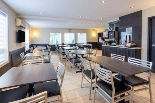 a restaurant with tables and chairs and a kitchen at Super 8 by Wyndham Quebec City in Quebec City