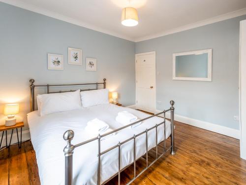 Schlafzimmer mit einem Bett mit weißer Bettwäsche und Holzböden in der Unterkunft Pass the Keys Stylish newly renovated Victorian 2 bedroom house in Shrewsbury