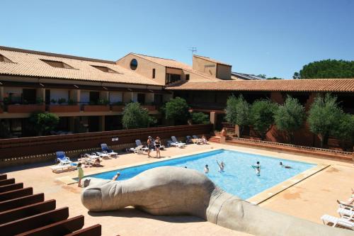 uma grande piscina com uma estátua de um cão reclinável em Lagrange Vacances Résidence du Golf em Saint-Cyprien