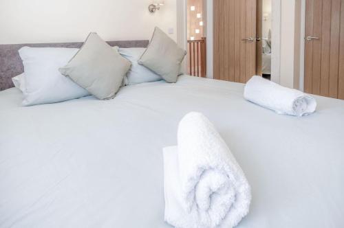 Una cama blanca con toallas encima. en Myrtle - 1 Bedroom Apartment - Saundersfoot en Saundersfoot