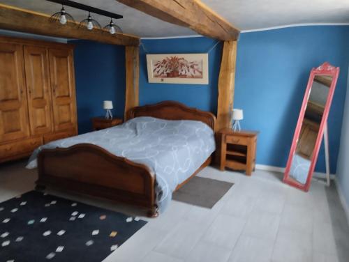une chambre avec un grand lit et un mur bleu dans l'établissement auxhirondelles, à Pouilly-sous-Charlieu