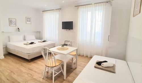 a white bedroom with a bed and a table and chairs at Adagio 1- Studio, Old Town in Corfu