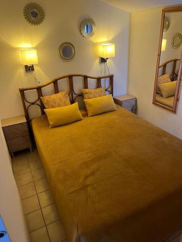 une chambre avec un grand lit avec des oreillers jaunes dans l'établissement Maison climatisée avec piscine, terrasse et place de parking privative, à Saintes-Maries-de-la-Mer