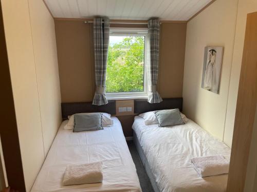 two beds in a small room with a window at Immaculate 3-Bed Lodge in Otley in Otley