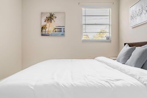 a white bedroom with a white bed and a window at Jacksonville Retreat: Unwind in Style at our Cozy Duplex Apartment in Jacksonville