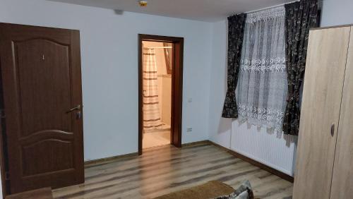 an empty room with a door and a window at Pensiunea Romosan in Cucuiş