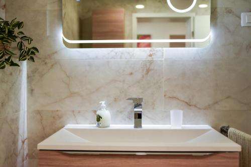 a bathroom sink with a mirror and a bottle of soap at SEDAMI in Maribor