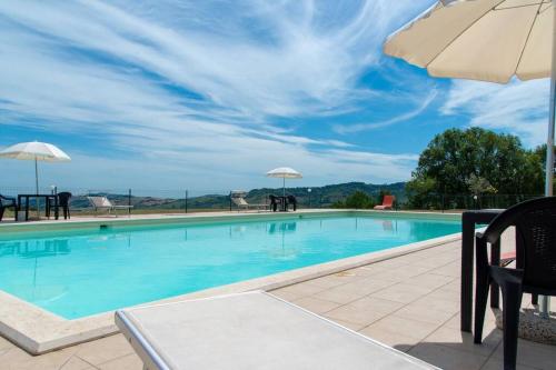 una piscina con sombrilla, mesas y sillas en L'Aurora B&B - Rural Villa With Private Pool & Panoramic View Near Montelparo, en Montelparo