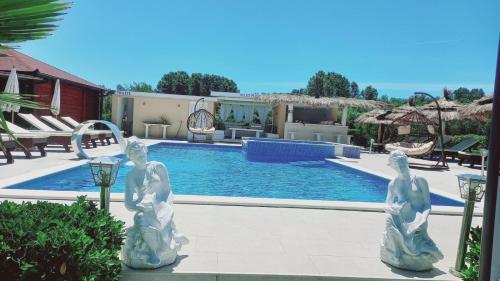 a pool with two statues in front of a resort at Christopher's apartments in Ulcinj