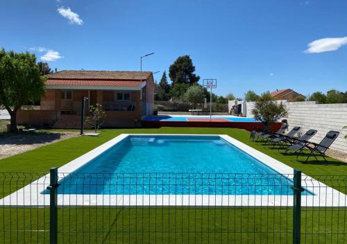 a swimming pool in a yard with a fence at Casa con piscina, Villa Alarilla in Fuentidueña de Tajo