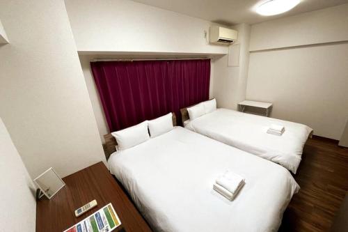 - 2 lits dans une chambre d'hôtel avec rideau rouge dans l'établissement PlusTom Stay-SHIMANOUCHI-, à Osaka