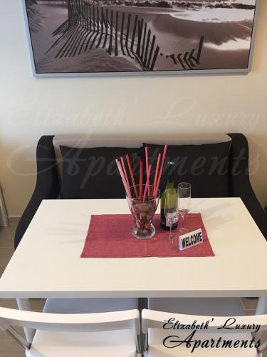 a white table with a glass of wine and chopsticks at Beachfront Luxury Apartments Elizabeth, Pomorie in Pomorie
