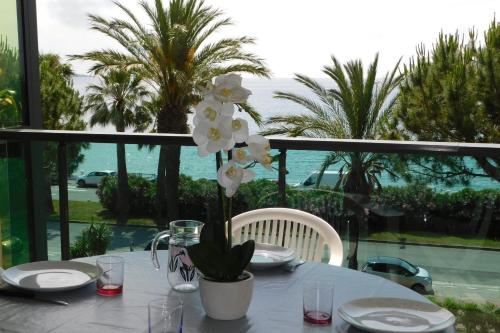 a table with white plates and a vase with flowers at Spacious 2-bedroom apartment in Egée residence with parking and air conditi in Cannes