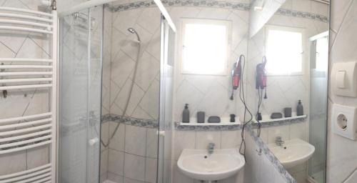 a white bathroom with a shower and a sink at Timbi Vendégház in Vonyarcvashegy