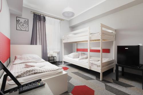 sypialnia z 2 łóżkami piętrowymi i telewizorem w obiekcie Moon Hostel Kraków w Krakowie