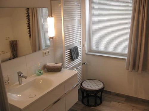 een badkamer met een wastafel, een spiegel en een kruk bij Ferienwohnung "Auszeit" - Familie Moll-Staudt, Langenargen am Bodensee in Langenargen