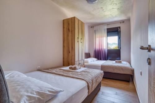 a small bedroom with two beds and a window at Apartmani Nikic -Tivat in Tivat