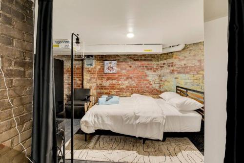 a bedroom with a bed and a brick wall at The Underground by East Grand in Detroit