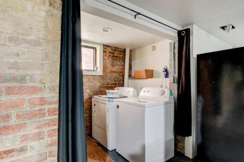 a kitchen with a washer and dryer and a brick wall at The Underground by East Grand in Detroit