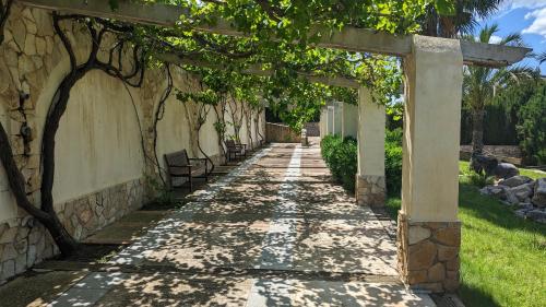 a stone walkway with an archway in a garden at El Collado in Cullera
