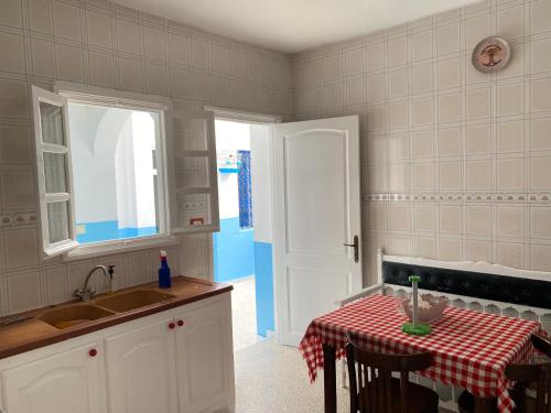 a kitchen with a table and a sink and a window at Le bien être in Kelibia