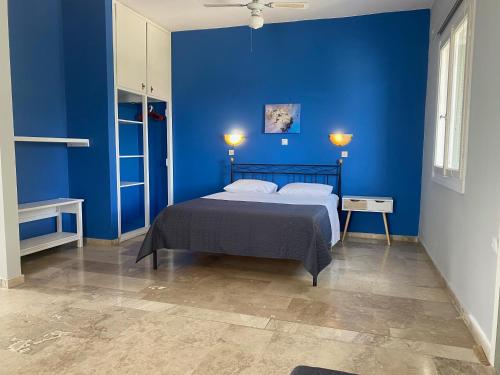 a blue bedroom with a bed and a blue wall at Daphne Bungalows in Tolo