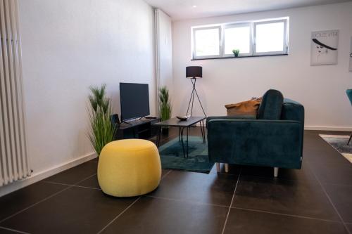 a living room with a couch and a yellow stool at Klassen Apartments! Erleben Sie Biberach in diesem Stilvollem Bungalow mit Charme und Komfort in Biberach an der Riß