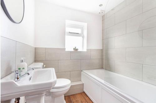 a white bathroom with a sink and a toilet and a tub at Cosy 2 bed with parking and garden in Cawston