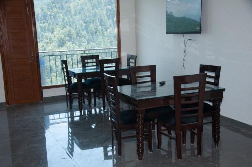 a dining room with a table and chairs and a window at Summer Hill Resort in Chail