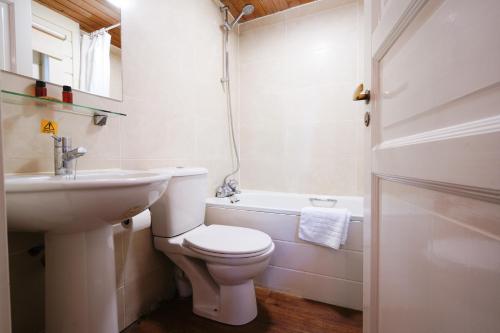 a bathroom with a toilet and a sink and a tub at Chevin Country Park Hotel & Spa in Otley