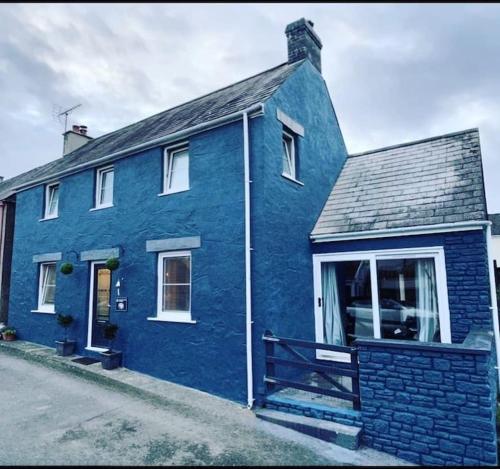 a blue house with a white window at Relaxing Riverside Cottage in Llangwm