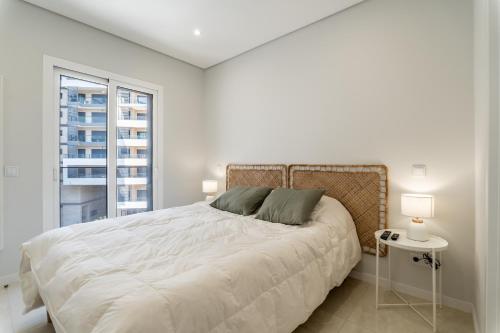 - une chambre blanche avec un grand lit et une fenêtre dans l'établissement Iate Residence, à Portimão