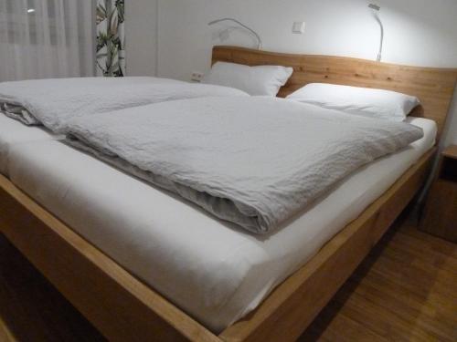 a bed with a wooden frame and white sheets at GOME in Meßkirch