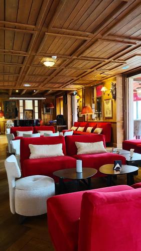 a room with red couches and tables and chairs at Les Violettes Hotel & Spa in Jungholtz