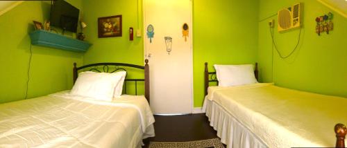 two beds in a room with green walls at Madie's Place Guest House in Santa Rosa