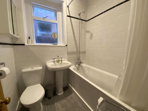 a bathroom with a toilet and a sink and a tub at Beautiful one bed garden flat in Muswell hill in London