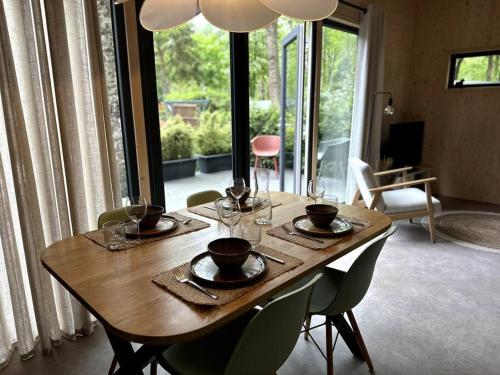 una mesa de madera con platos y copas de vino. en FIKA Luxe vakantiewoning voor 4 personen @ Veluwe en Hoenderloo