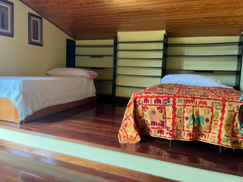 a bedroom with two beds and wooden floors at Villa do Sil in Sober
