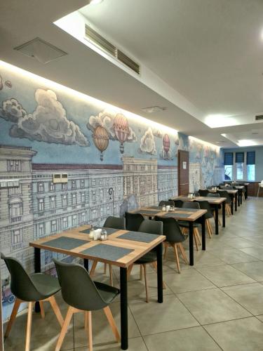 a dining room with tables and chairs and a mural at Medos Hotel in Budapest