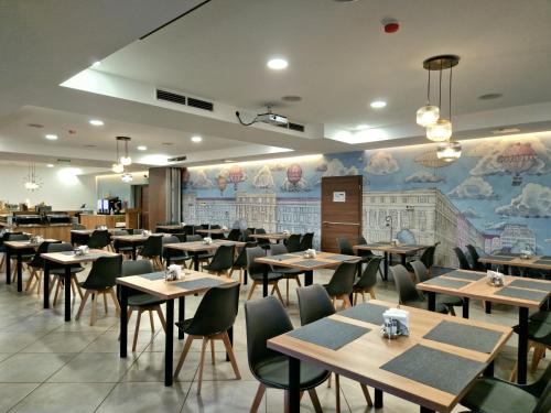ein Restaurant mit Tischen und Stühlen und einem Wandbild in der Unterkunft Medos Hotel in Budapest