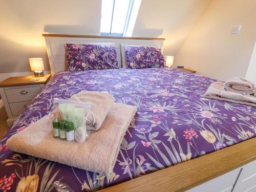 勞斯的住宿－Saddle Rack Cottage，一间卧室配有一张紫色床,提供毛巾和瓶子